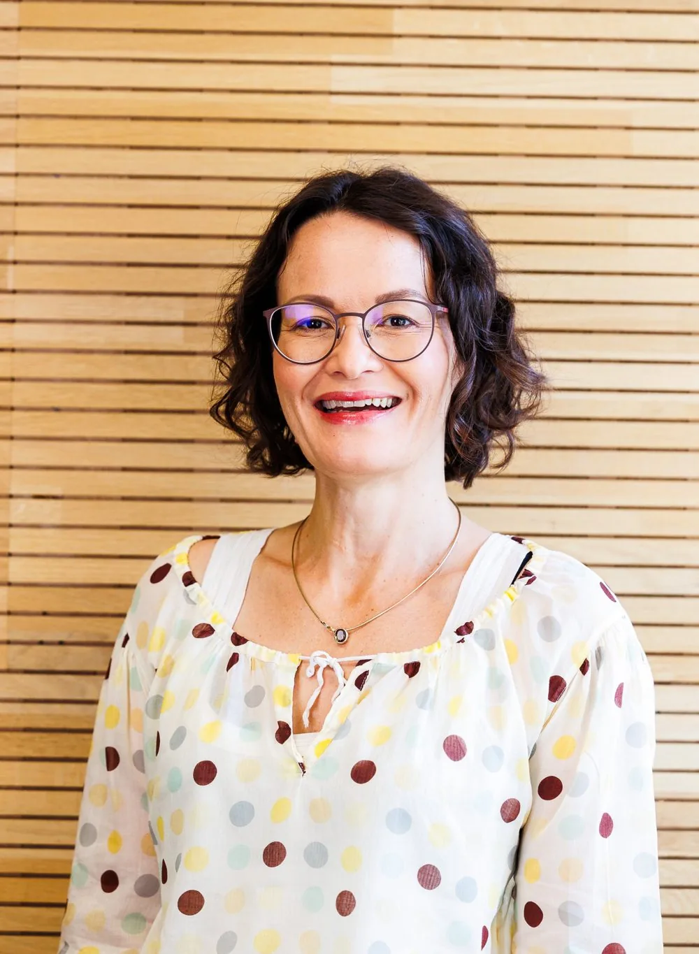 Julia Drowatzky lacht vor einer Holzwand