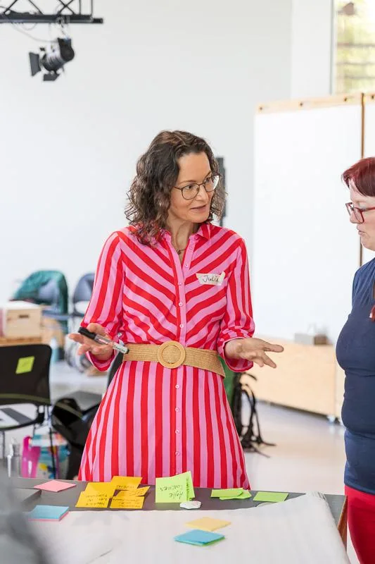Julia Drowatzky im Workshop an einem Tisch voller Karten